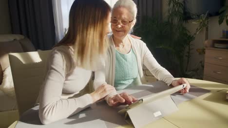 Cheerful-Woman-and-Grandmother-Using-Digital-Tablet-Together