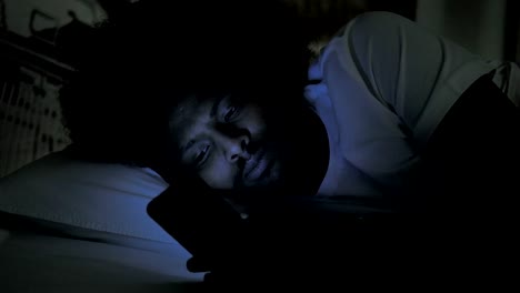 African-Man-Using-Phone-in-Bed-at-Night