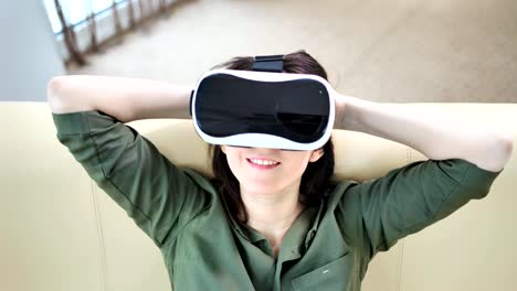 High-angle-portrait-of-smiling-young-woman-putting-on-modern-virtual-reality-glasses