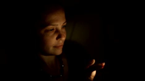 a-middle-aged-Caucasian-woman-sitting-at-night-in-a-room-on-the-couch-with-a-smartphone-and-communicates-with-friends-on-social-networks