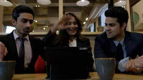 Handheld-shot-of-young-Indian-coworkers-colleagues-huddled-together-as-they-work-on-computer-and-work-out-a-solution-and-they-celebrate-with-high-five-hands-and-smile