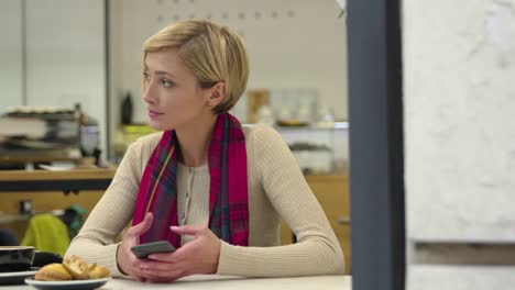 Upset-Woman-With-Mobile-Phone-Waiting-At-Table-In-Cafe