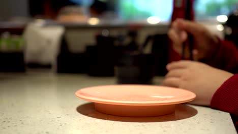 Little-girl-eats-sushi-at-a-Japanese-restaurant.-The-little-girl-is-wearing-a-hearing-aid.