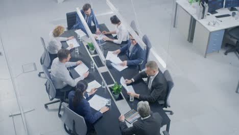 In-the-Corporate-Office-Meeting-Room-Group-of-Businesspeople,-Investors,-Executives-and-Members-of-the-Board-of-Directors-Talking,-Negotiating-and-Working-on-a-Winning-Strategy.-High-Angle-Camera-Shot