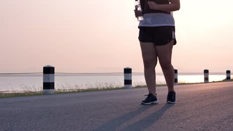 Overweight-Asian-women-jogging-in-the-street-in-the-early-morning-sunlight.-concept-of-losing-weight-with-exercise-for-health.-Slow-motion,-Bottom-view