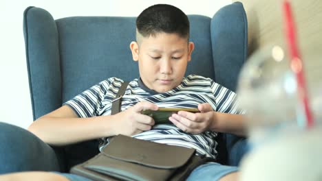 Young-teenager-playing-game-on-smartphone-in-cafe