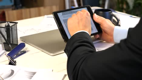 Male-hands-of-young-businessman-developing-a-business-project-and-analyzing-statistical-data-information-on-a-tablet-pc.-Successful-entrepreneur-working-on-modern-digital-device-in-office.-Close-up