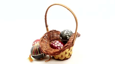 decorative-basket-with-painted-Easter-eggs-on-white-background