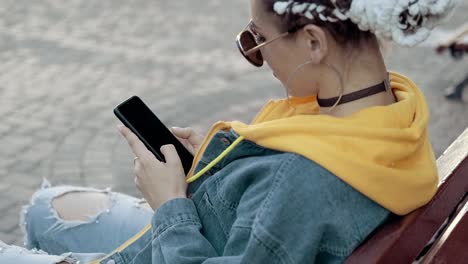 Woman-texting-with-mobile-phone,-typing-text-message-sitting-at-bench