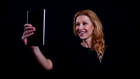 Closeup-portrait-of-adult-attractive-redhead-female-having-a-video-call-on-the-tablet-with-background-isolated-on-black