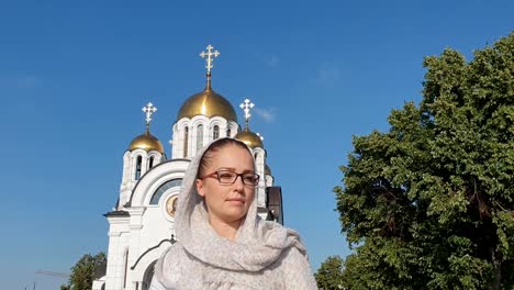 Orthodoxe-Lifestyle-Frau-im-Schal-steht-auf-dem-Hintergrund-der-orthodoxen-Kirche