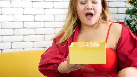 Overweight-woman-receiving-gift-box-with-hamburger-on-christmas's-day