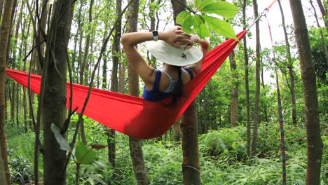 Mujer-relajándose-en-hamaca-con-teléfono-inteligente-en-la-selva-tropical,4k