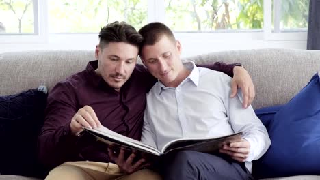 Pareja-gay-relajándose-en-el-sofá,-libro-de-lectura.