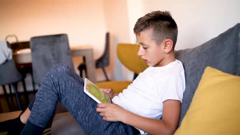 Young-boy-is-playing-games-on-his-tablet-at-home