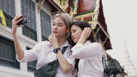 Smiling-Asian-lesbian-couple-using-smartphones-taking-selfies-a-photo.-Beautiful-Asian-women-traveling-with-a-friend's-vacation-lifestyle.