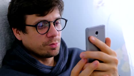 Happy-young-man-in-glasses-speaking-video-chat-on-smartphone,-face-close-up.