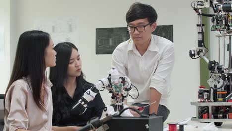 Asiatische-Teenager-Ingenieur-Montage-und-Testen-von-Robotik-Antworten-im-Labor.-Architekten-Design-Circuit-Meeting-teilen-Technologieideen-und-kooperierende-Entwicklungsroboter.