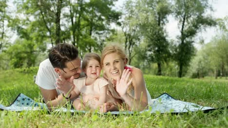 CLOSE-UP:-Perfekte-junge-glückliche-Familie-mit-fröhlichen-schönen-Mädchens-winken