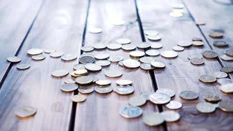 Pile-of-coins-falling-on-the-wooden-table