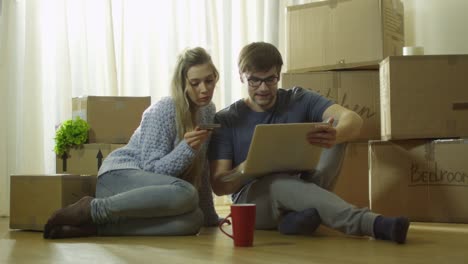 Young-Couple-nutzt-Laptop-für-Online-Shopping-im-neuen-Haus-Schuss-auf-RED-Cinema-Camera-in-4K-(UHD).