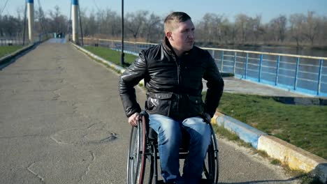 Disabled-man-pushes-himself-in-wheelchair-near-the-river,-Portrait-male