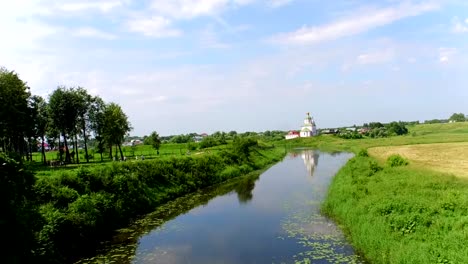 Antena-tiro-río-Kamenka-e-Iglesia-de-la-antigua-ciudad-de-Suzdal,-Rusia