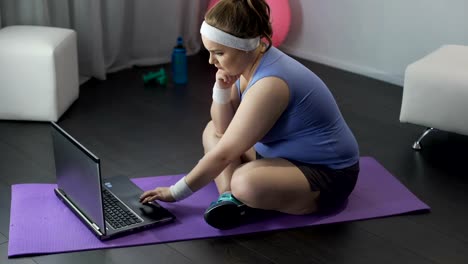 Plump-woman-browsing-on-laptop-training-results-of-online-weight-loss-marathon