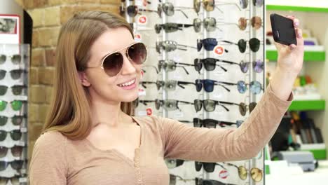 Mujer-joven-feliz-tomar-autorretratos-mientras-está-de-compras-para-gafas