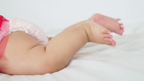 Baby-girl-lying-on-her-stomach-and-swing-her-legs-to-try-to-crawl-in-slow-motion-shot