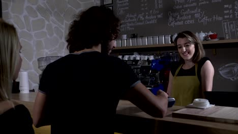 Teenagers-female-and-male-customers-paying-with-crypto-currency-bitcoin-from-mobile-app-and-ordering-coffee-to-go-in-slow-motion