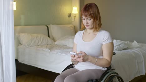 Mujer-en-silla-de-ruedas-tecleando-en-el-teléfono-móvil