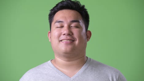 Young-handsome-overweight-Asian-man-against-green-background