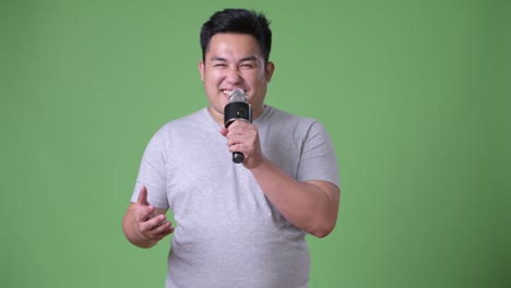 Young-handsome-overweight-Asian-man-against-green-background