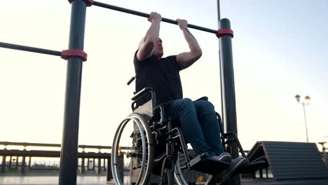 Young-disabled-man-in-wheelchair-engaged-on-the-crossbar-outdoors