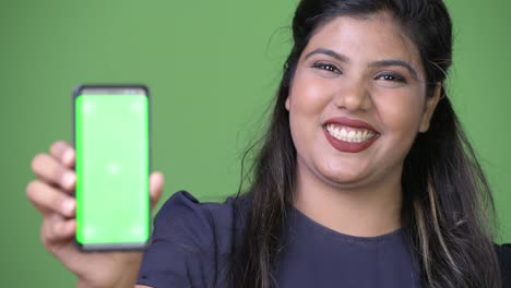 Young-overweight-beautiful-Indian-businesswoman-against-green-background