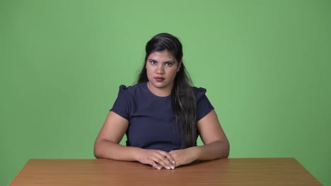 Young-overweight-beautiful-Indian-businesswoman-against-green-background