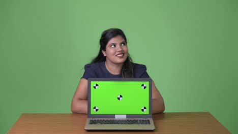 Young-overweight-beautiful-Indian-businesswoman-against-green-background