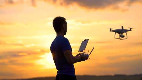 Das-Männchen-steuert-Quadrocopter-auf-dem-Sonnenuntergang-Hintergrund