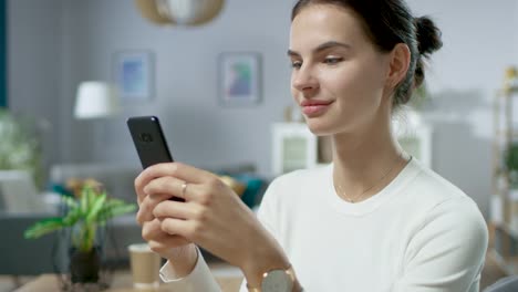 Retrato-de-la-hermosa-joven-mujer-utilizando-Smartphone,-navegando-en-Internet,-revisar-redes-sociales-mientras-se-sienta-en-casa.