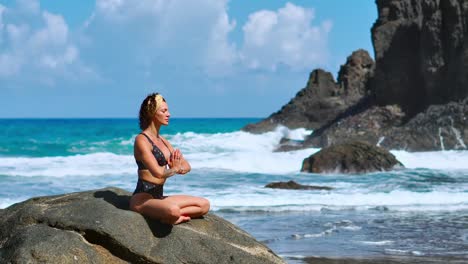 Ruhige-Meditation-Yoga.-Brünette-touristischen-Frau-meditieren-im-Lotussitz-auf-Felsvorsprung-über-dem-malerischen-Praia-da-Marinha.-Meditieren-Weibchen-auf-den-Klippen-der-Kanarischen-Inseln