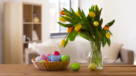 huevos-de-Pascua-en-cesta-y-tulipán-flores-en-casa