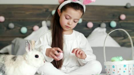 Chica-jugando-con-conejo-y-huevos-de-Pascua-en-la-cama