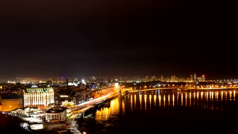 Time-lapse-video-at-night-of-big-city,-embankment-end-wide-river-with-water-waves-from-floating-boat-create-lighting-effect