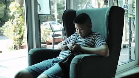 Young-teenager-playing-game-on-smartphone-in-cafe