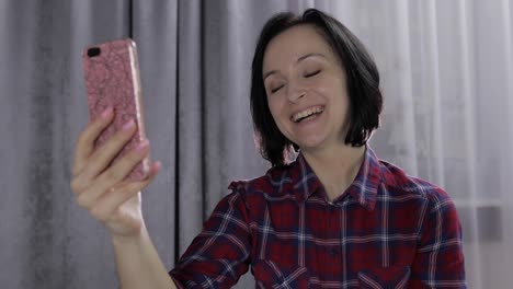 Young-woman-on-bedroom-enjoying-having-video-chat-using-smartphone