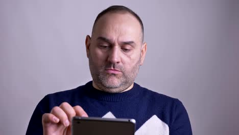 Tiro-de-primer-plano-del-hombre-caucásico-de-mediana-edad-navegando-en-la-tableta-y-luego-mirandoun-a-la-cámara-y-sonriendo.