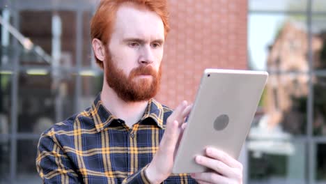 Rotschopf-Bart-junger-Mann-mit-Tablet-im-Freien