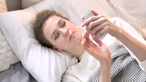 Top-View-of-Young-Woman-Using-Smartphone-in-Bed,-Browsing