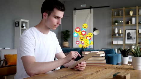 Glücklicher-junger-Mann-mit-Tablet,-fliegende-Emojis,-Smileys-und-Likes